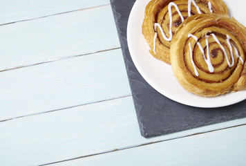 A plate of freshly baked cinnamon swirls on a blue wooden dining table background with blank space...
