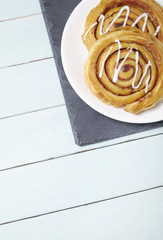 A plate of freshly baked cinnamon swirls on a blue wooden dining table background with blank space below