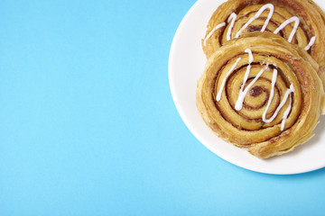 A plate of freshly baked cinnamon swirls on a bright blue background with blank space at side