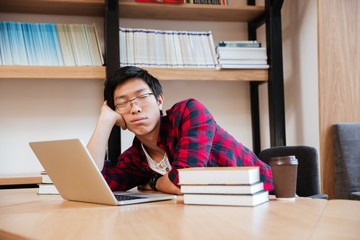 Man sleeping at the library near laptop and books