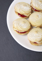 A close up of a plate full of freshly baked Viennese whirl biscuits on a rustic slate background