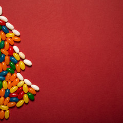 Christmas tree from colorful candies on red paper background. 