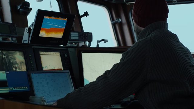 Captain of Commercial Fishing Ship Surrounded by Monitors and Screens Working with Sea Maps in his Cabin. Shot on RED Cinema Camera in 4K (UHD). 