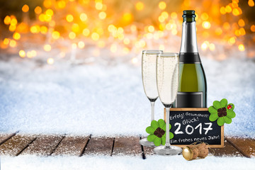 2017 Silvester bokeh Hintergund mit Sektflasche Sektgläsern Tafel mit Grüßen und Wünschen im...