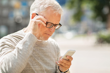 senior man texting message on smartphone in city