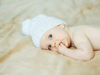 Little baby boy in white hat with fingers in mouth