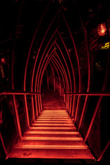 Rote Treppe mit Pforte führt hinab in die Dunkelheit