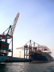 Shipping harbor or container harbor with freight ship and harbor crane in the sunset.