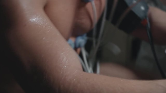 Tilt up of male determined athlete in oxygen mask cycling during cardiopulmonary testing while being observed by his doctor