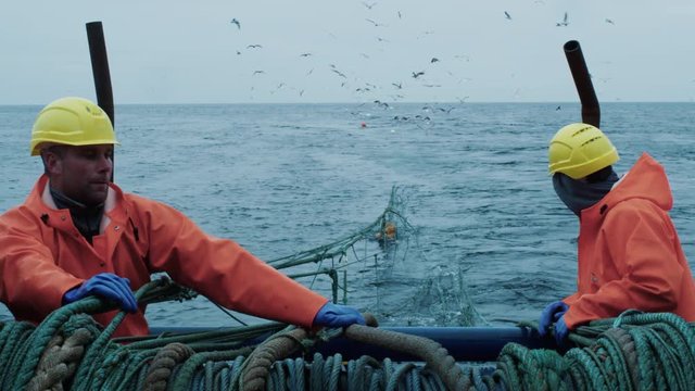 Crew of Fishermen Work on Commercial Fishing Ship that Pulls Trawl Net. Shot on RED Cinema Camera in 4K (UHD). 