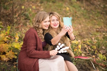 Two smiling women take a selfie in autumn Park