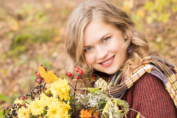 Cute woman with a bouquet of flowers in autumn park