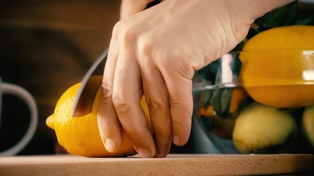 Man cutting whole lemon and making juice with a juicer. 4K closeup shot