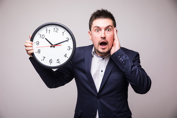 Worried bearded young man in suit with clock in hands miss something