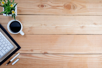 Office desk table with smartphone, pen on notebook, cup of coffee and flower. Top view with copy space (selective focus)..