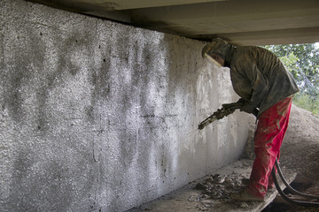 Worker renews concrete viaduct with sprayed concrete