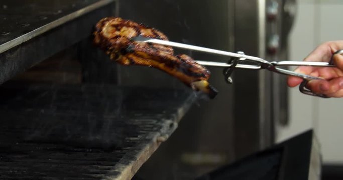 Chef prepares bone steak 4k video: takes meat from grill charcoal oven. Cooking  process on barbecue restaurant kitchen 