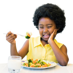 African kid pulling ugly face at dinner table.