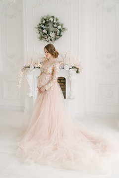 beautiful pregnant woman near the fireplace with Christmas decorations