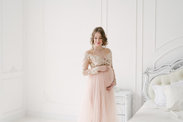 Pregnant woman in a white bedroom with New Year's decor