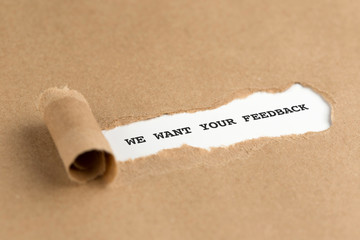 The text WE WANT YOUR FEEDBACK appearing behind torn brown paper