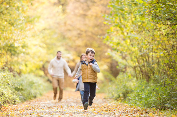 Naklejka na ściany i meble Beautiful young family on a walk in autumn forest.