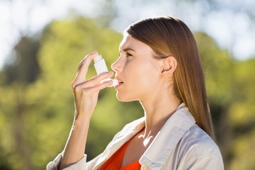 Woman using asthma inhaler - obrazy, fototapety, plakaty
