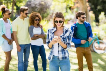 Woman using mobile phone with friends in background