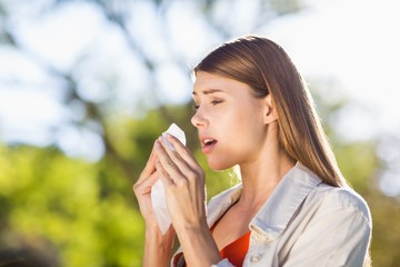 Beautiful woman using tissue while sneezing