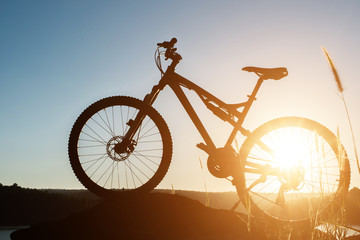 Fototapeta premium Silhouette Mountain biking on the rock at sky sunset