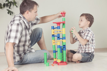 Obraz premium Daddy with little boy playing with toy on the floor at the day t
