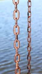 Metal chain links above water.