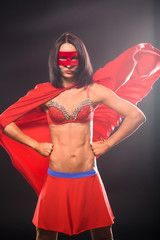 Young super hero woman isolated on black background in studio. Young confident woman in super hero costume.