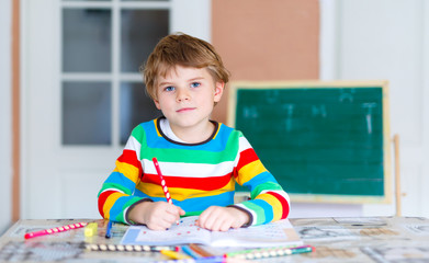 Happy school kid boy at home making homework