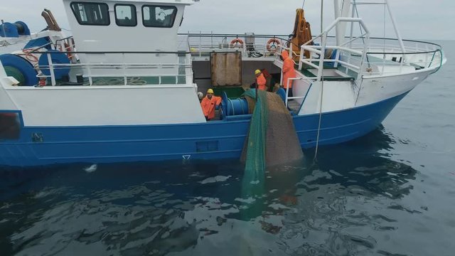 Flying Towards a Commercial Ship Fishing with Trawl Net at the Sea. Smiling Fisherman Looking at Camera. Shot on RED Cinema Camera in 4K (UHD). 