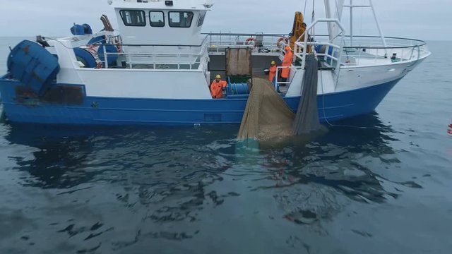 Zoom out of a Commercial Ship Fishing with Trawl Net on the Sea. Shot on RED Cinema Camera in 4K (UHD). 