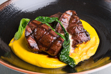 Grilled steak served with yellow humus