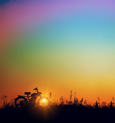Fantasy picture bright colorful sky and silhouette of an old motorcycle in a simple evening twilight at sunset.
