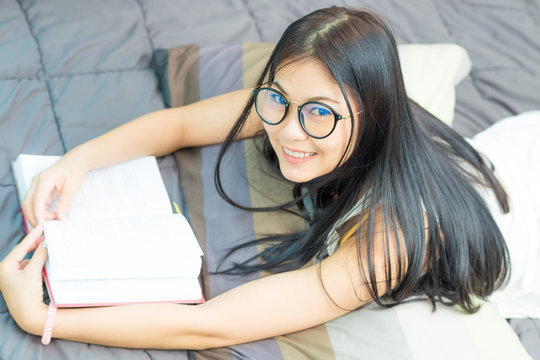Attractive nerd student woman on bed reading book
