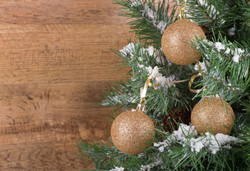 Gold Ornaments on a Christmas Tree Against a Wooden background