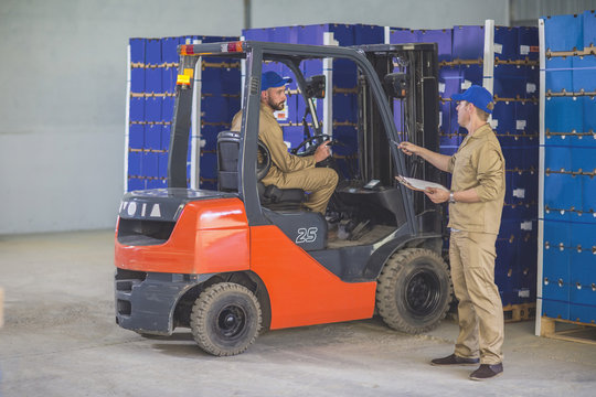 Worker stocking load with forklift