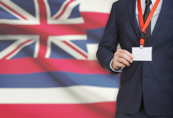 Businessman holding badge on a lanyard with USA state flag on background - Hawaii