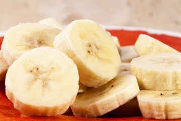Slices of fruit of banana on red plate , close up