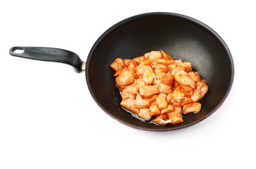 Raw chicken fillet cutted into pieces and spiced in black pan isolated over white background