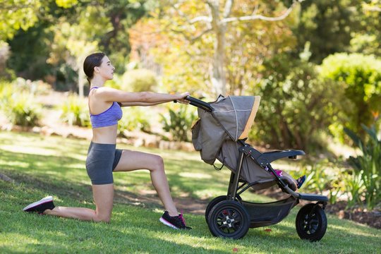 Young woman exercising with baby stroller 