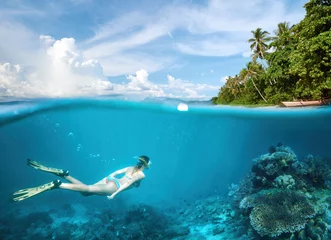 Foto auf Acrylglas Tauchen Young woman snorkeling in clear tropical waters in near of exotic island.
