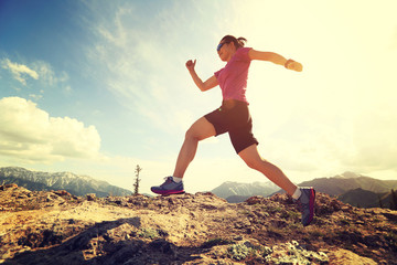 healthy young woman trail runner running on beautiful mountain peak