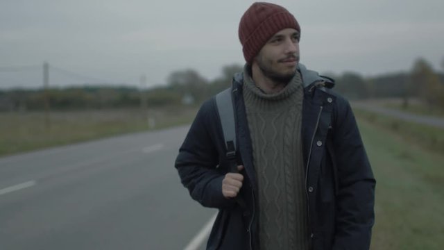 Casualy Dressed Traveler Walking along the Highway at a Cloudy Day. Shot on RED Cinema Camera in 4K (UHD).