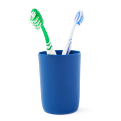 Pair of toothbrushes in blue plastic cup isolated over white background