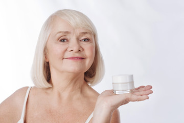 Pleasant smiling woman having a cream bottle in her hand